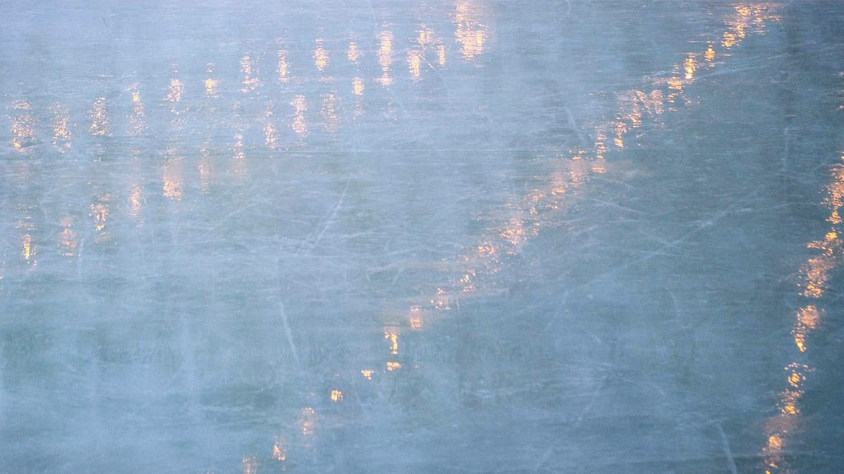 An abstract image of blue ice with golden lights reflecting off the surface