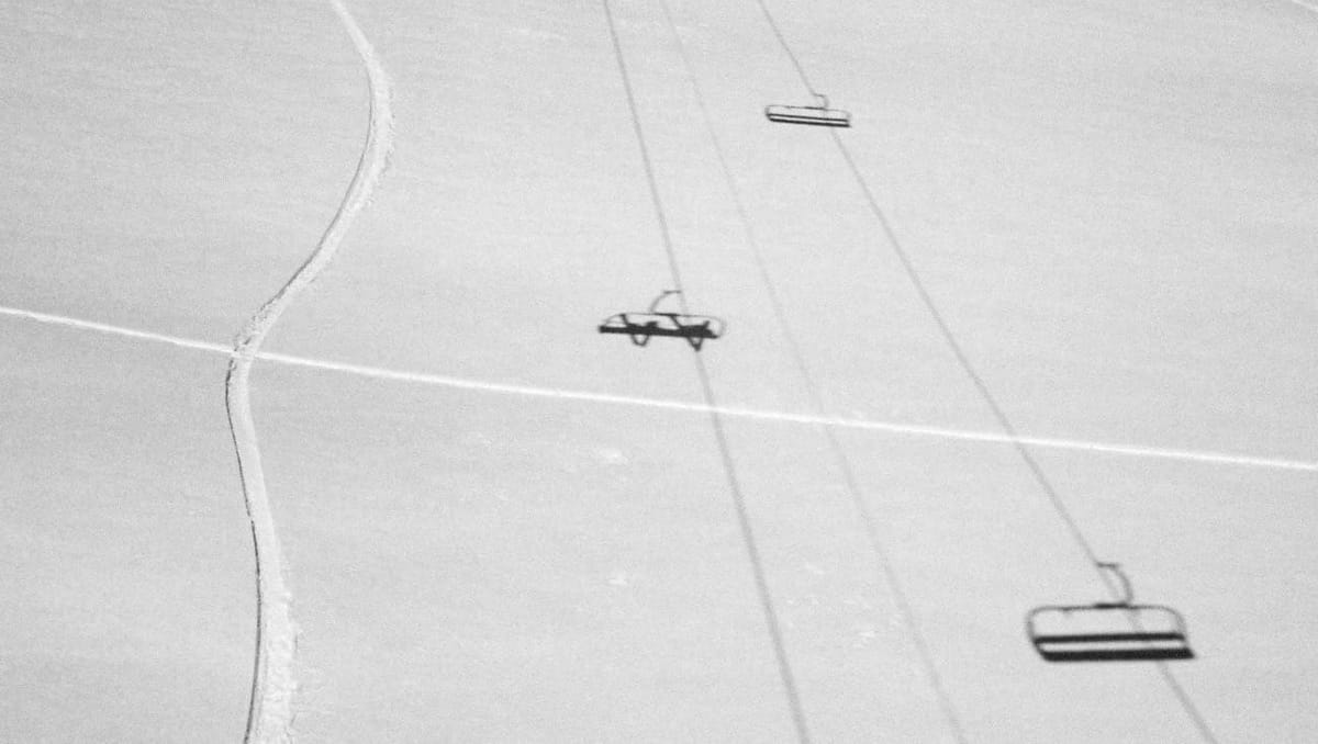 A ski hill with shadows of the chair lift overhead