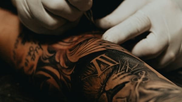 A closeup view of a tattoo artist working on a client's arm.